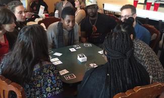 People sitting around a table, playing the card game Loud and Proud.